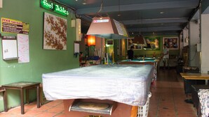 Une salle de billard avec un panneau néon, une table de billard et une table de jeu de flipper.