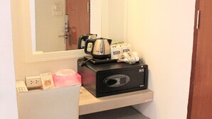 Une petite cuisine équipée comprenant un micro-ondes, un grille-pain et une machine à café sur le plan de travail, un petit réfrigérateur en dessous et un miroir au-dessus.