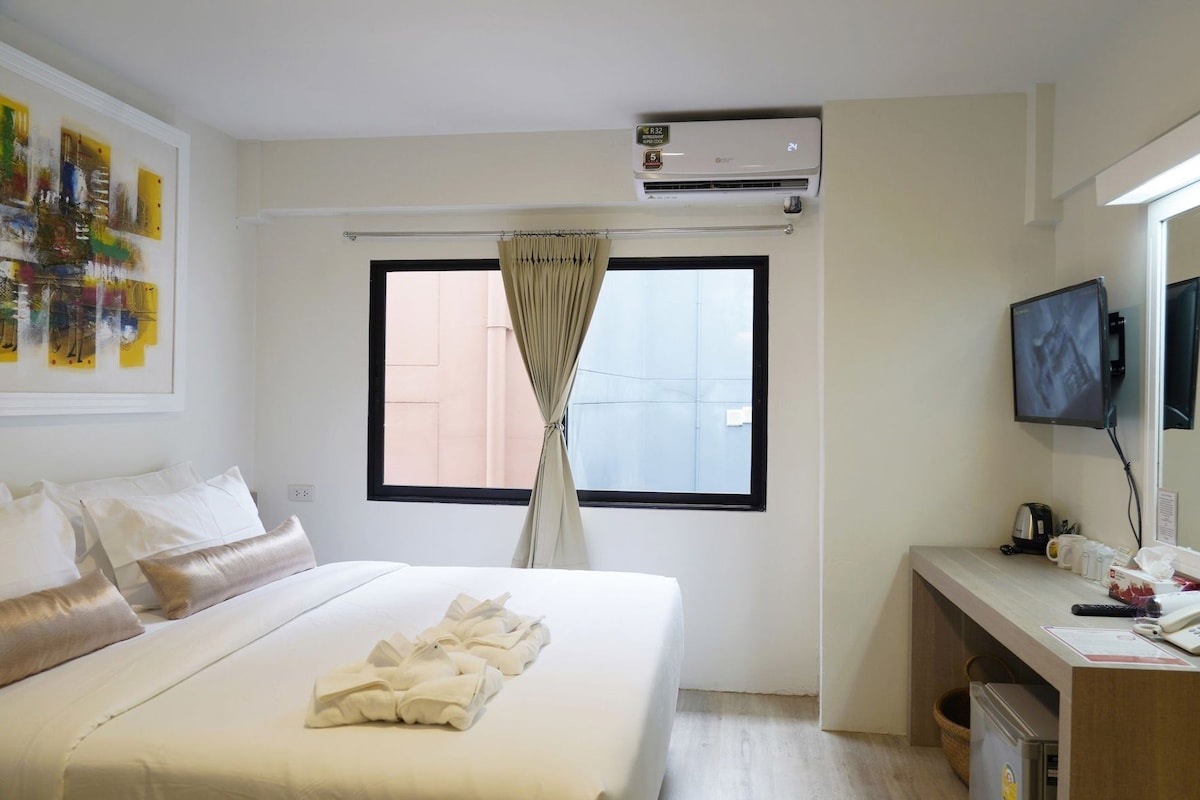 Una habitación de hotel con cama, escritorio, televisión y aire acondicionado.