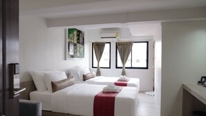 Une chambre d’hôtel avec deux lits, un bureau et un appareil de climatisation.