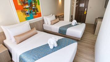 A hotel room with two beds, a painting on the wall, and a coat rack.
