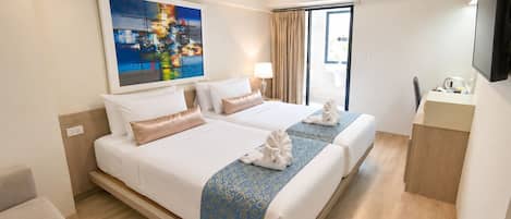 A hotel room with a large bed, a desk, a television, and a painting on the wall.