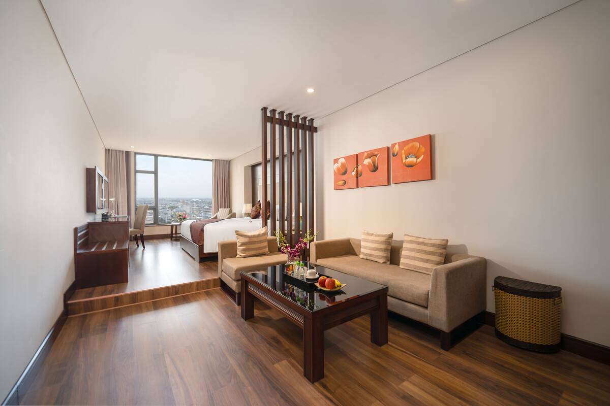 A modern hotel room with a sofa, coffee table, and a view of the city.