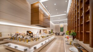 A modern buffet setup with multiple serving stations, a central serving area, and a long counter with food and drink options. - Minh Toan Galaxy Hotel (Da Nang)