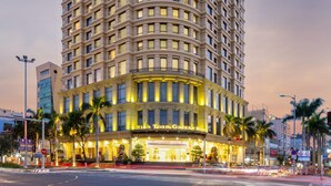 A multi-story hotel with a curved facade, illuminated windows, and a prominent entrance with a statue. - Minh Toan Galaxy Hotel (Da Nang)
