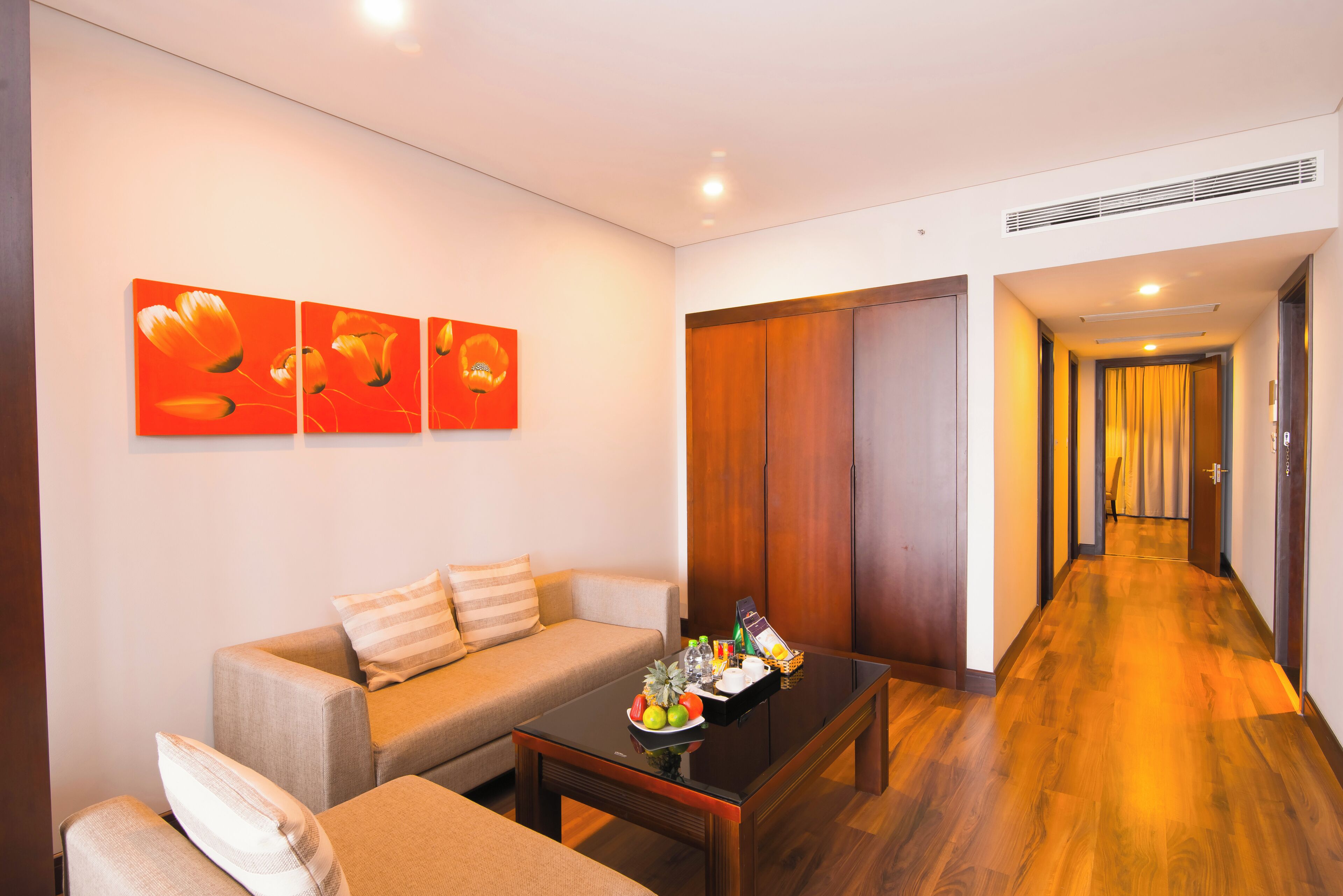 A modern living room with a sofa, a coffee table with fruits, and a wooden door.