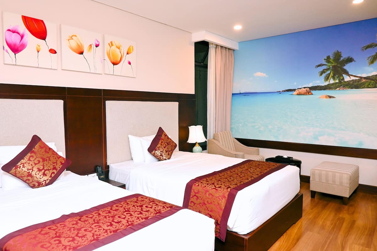 A hotel room with two beds, a large window with a beach mural, a small table, and a chair.