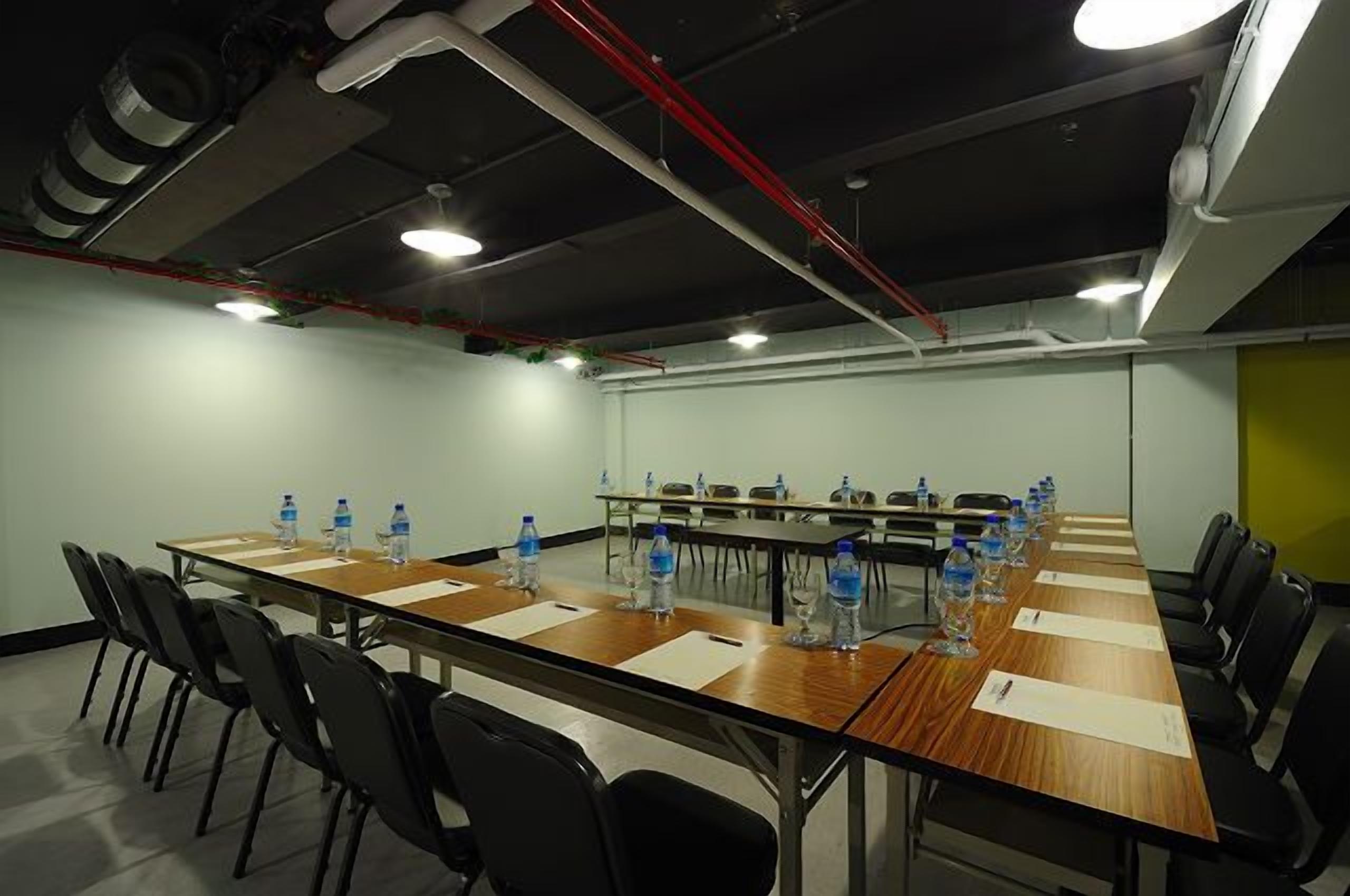 A conference room with a long table, black chairs, water bottles, and a whiteboard.