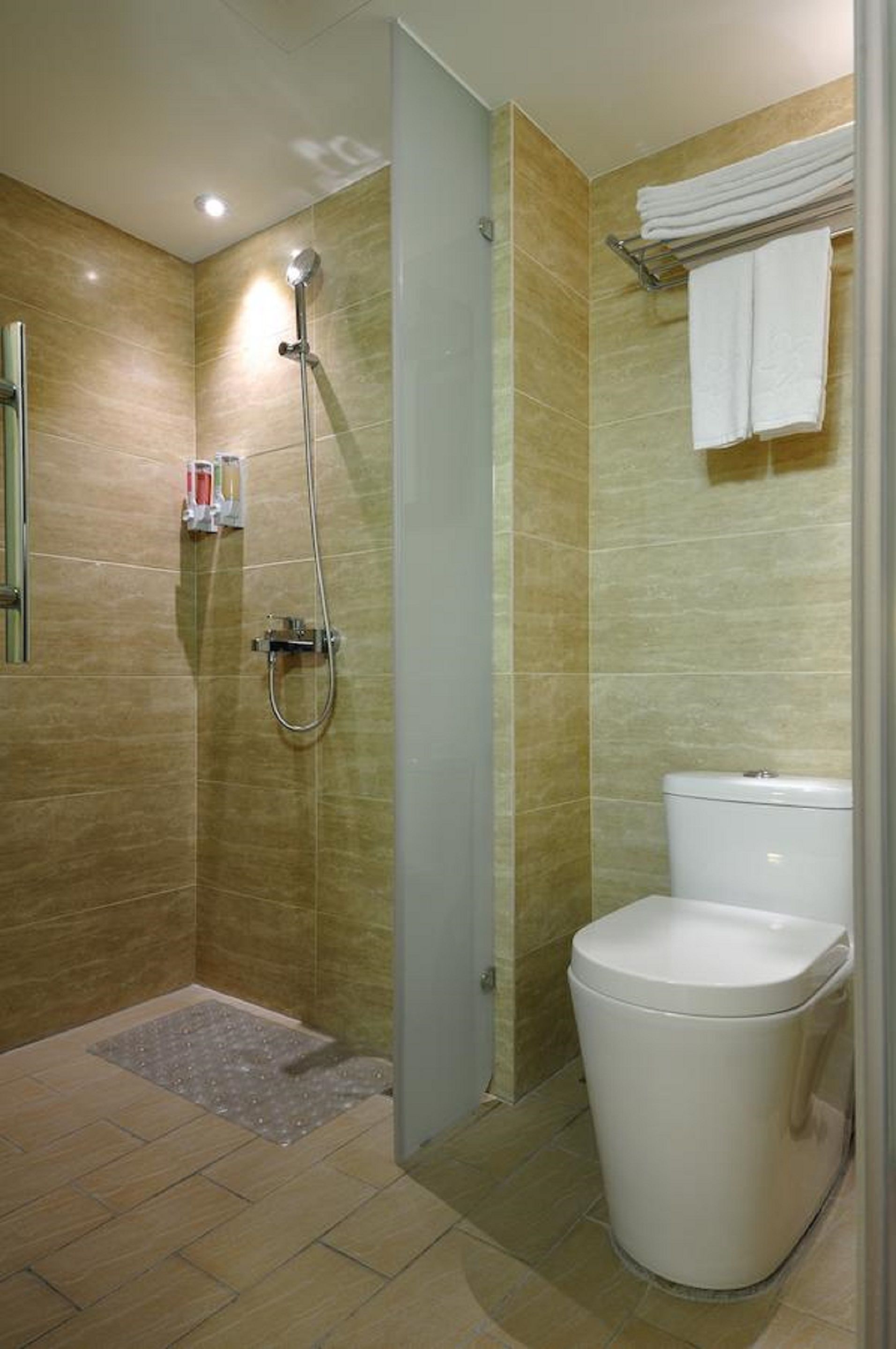 A bathroom with a shower, toilet, and a towel rack.