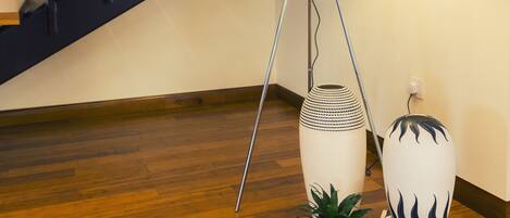 A modern interior with a wooden staircase, a floor lamp, and two decorative vases.