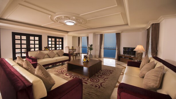 A spacious living room with a large sofa, a coffee table, and a view of the sea. - Roda Amwaj Suites (Dubai)