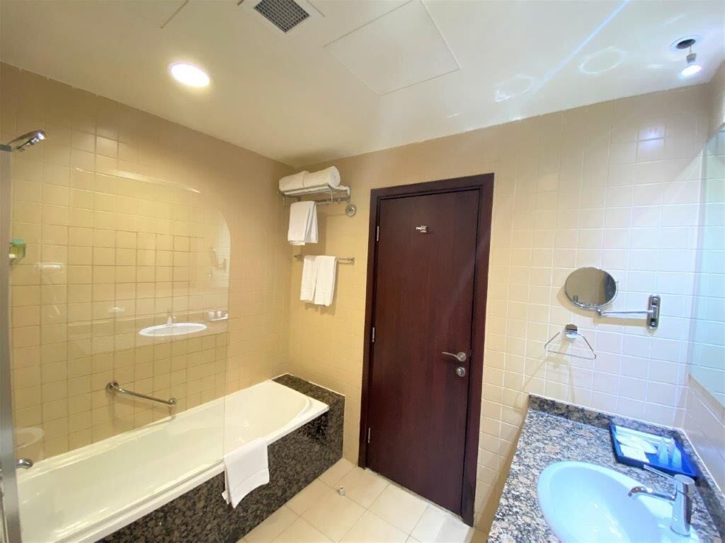 Une salle de bain avec une baignoire, un lavabo, un miroir et une porte.