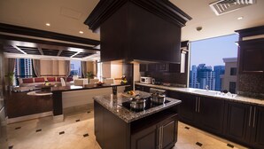 A modern kitchen with dark cabinetry, a central island with a stove, and a large window offering a city view. - Roda Amwaj Suites (Dubai)