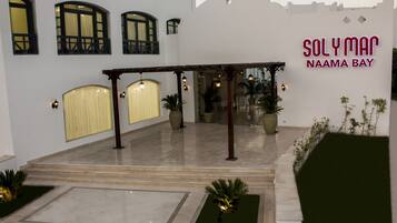 A hotel entrance with a covered patio area, potted plants, and a sign reading "Sol y Mar Naama Bay".