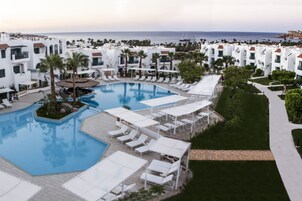 Et resort med en stor swimmingpool, liggestole og havudsigt.