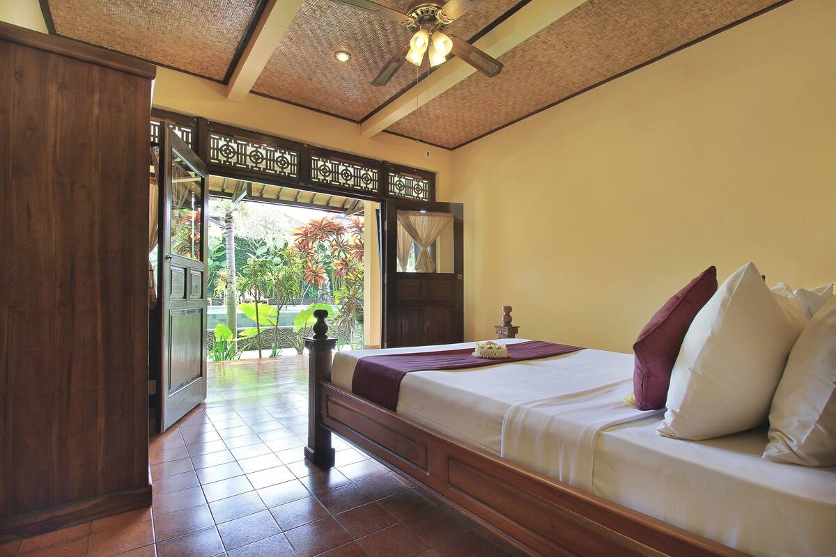 A bedroom with a bed, wooden headboard, and a ceiling fan.