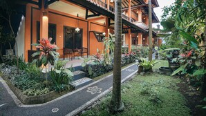 Un edificio tradicional con balcón, rodeado de abundante vegetación y un camino empedrado.