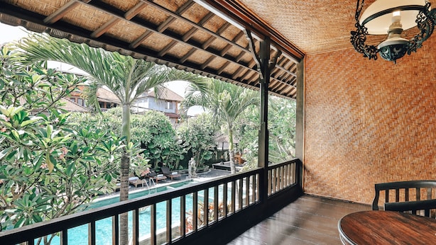 Un espacio al aire libre techado con piscina, terraza de madera y vistas a zonas verdes y edificios.