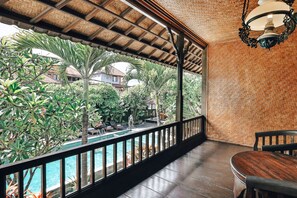 Un espace extérieur abrité comprenant une piscine, une terrasse en bois et une vue sur la végétation et les bâtiments environnants.