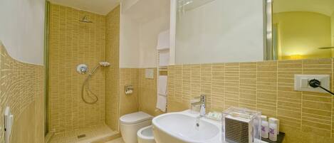 A bathroom with a shower, toilet, and sink, featuring tiled walls and a mirror.