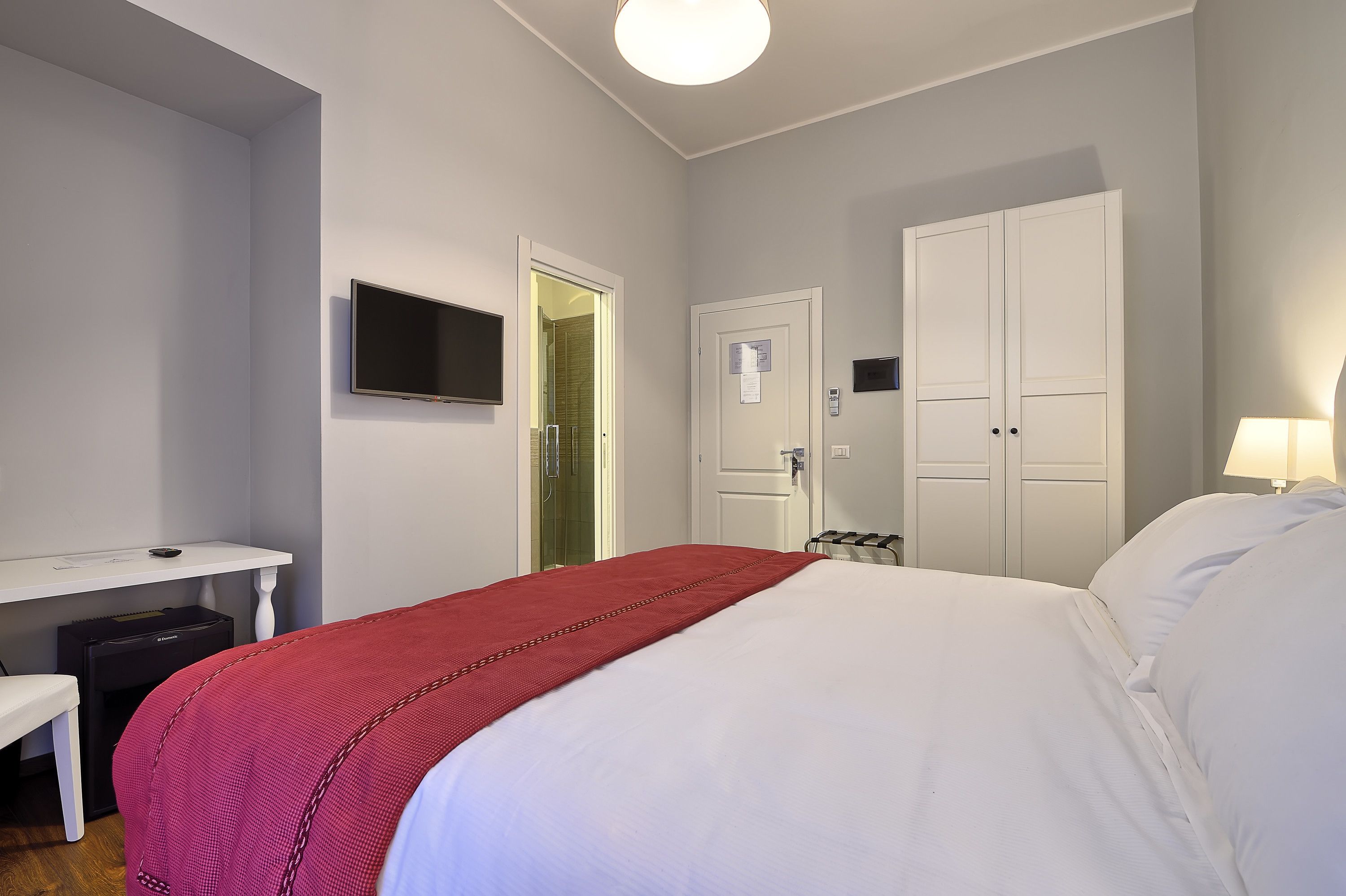 A hotel room with a bed, a desk, a TV, and a wardrobe.