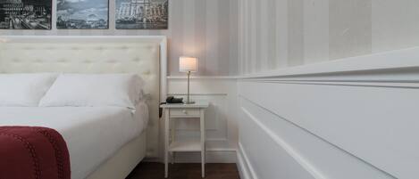 A hotel room with a large bed, a nightstand with a lamp, and three cityscape pictures on the wall.