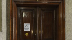 Una puerta doble de madera oscura con un cartel que indica 'Star Vatican Rooms' y un número de teléfono.
