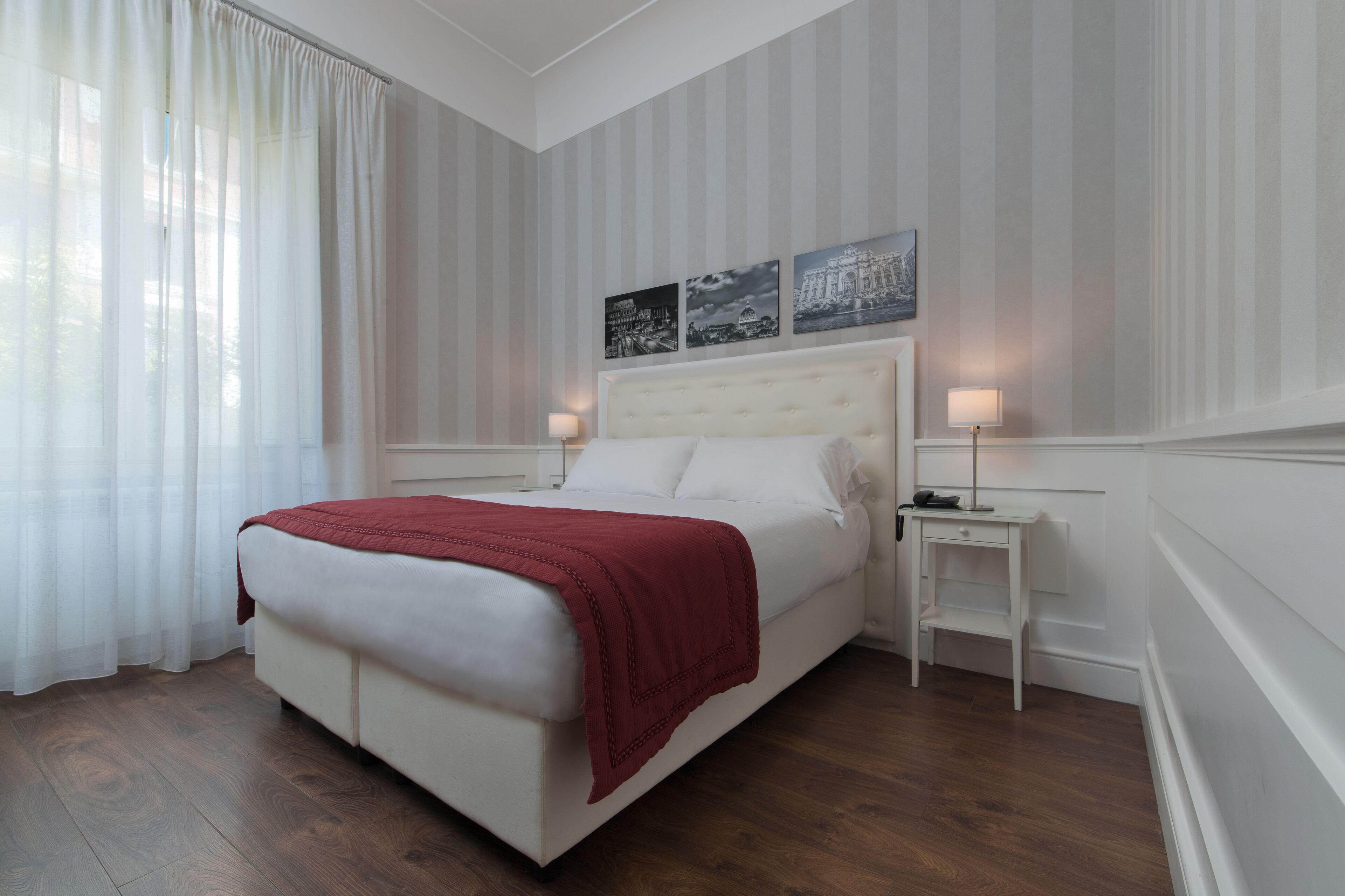 Una habitación de hotel ordenada con una cama grande, una mesita de noche y una pequeña mesa.