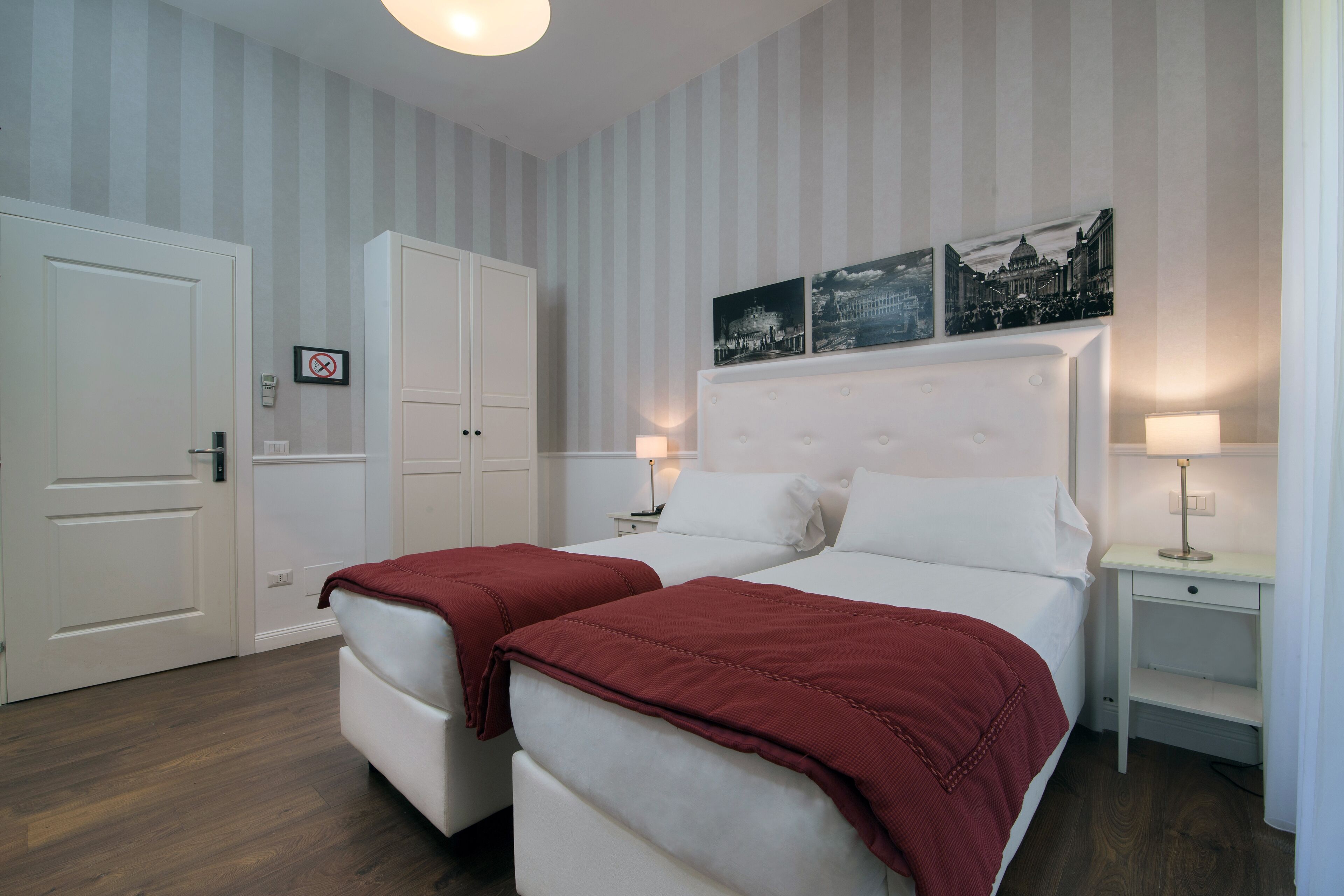 A hotel room with two beds, a wardrobe, and a door with a 'Do Not Enter' sign.