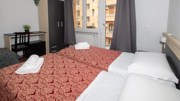 Una habitación de hotel con cama, escritorio, silla y ventana con vistas a edificios.