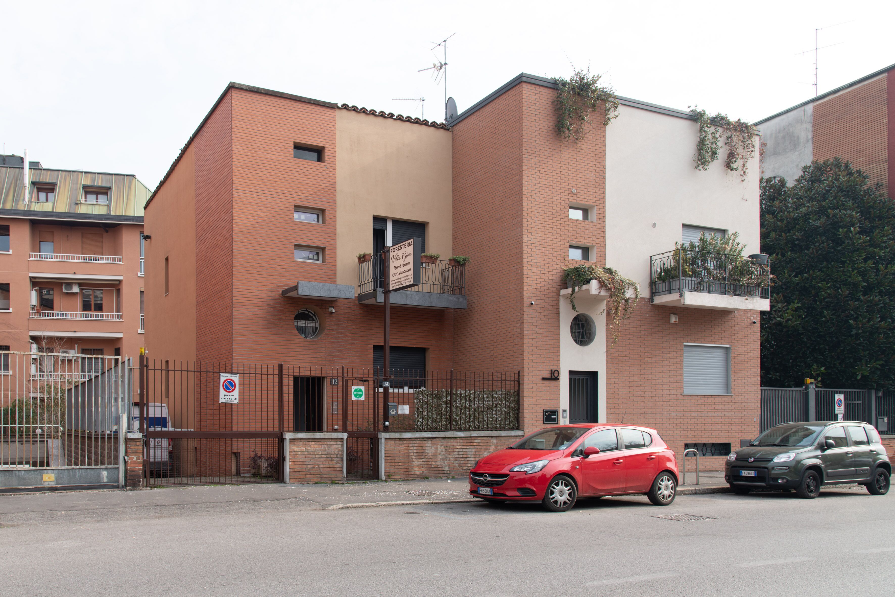 A red car parked in front of a building with a sign indicating a restaurant.