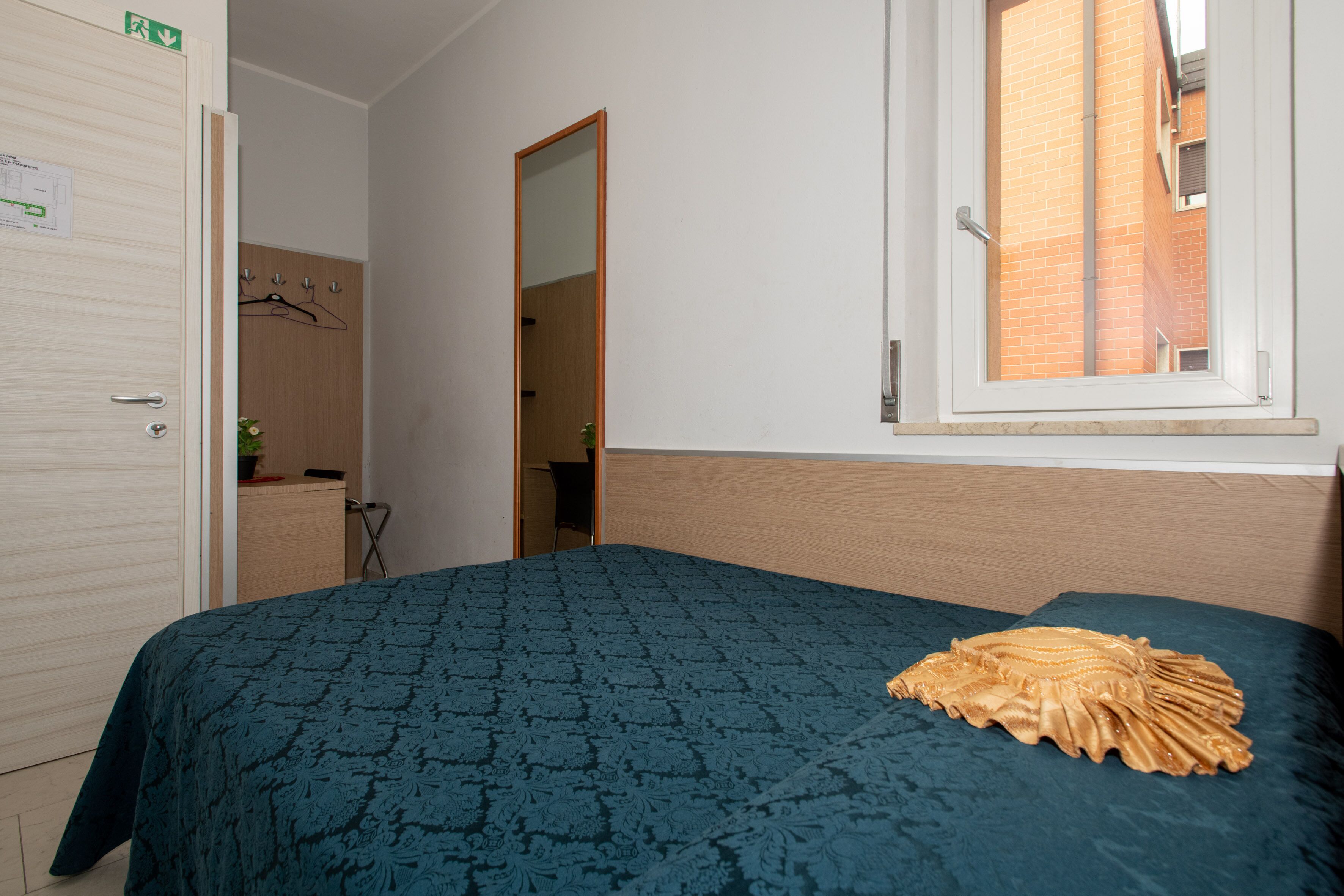 A bedroom with a bed, a wardrobe, a mirror, and a window.