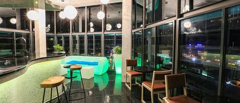 A modern lounge area with a pool table, bar stools, and seating.