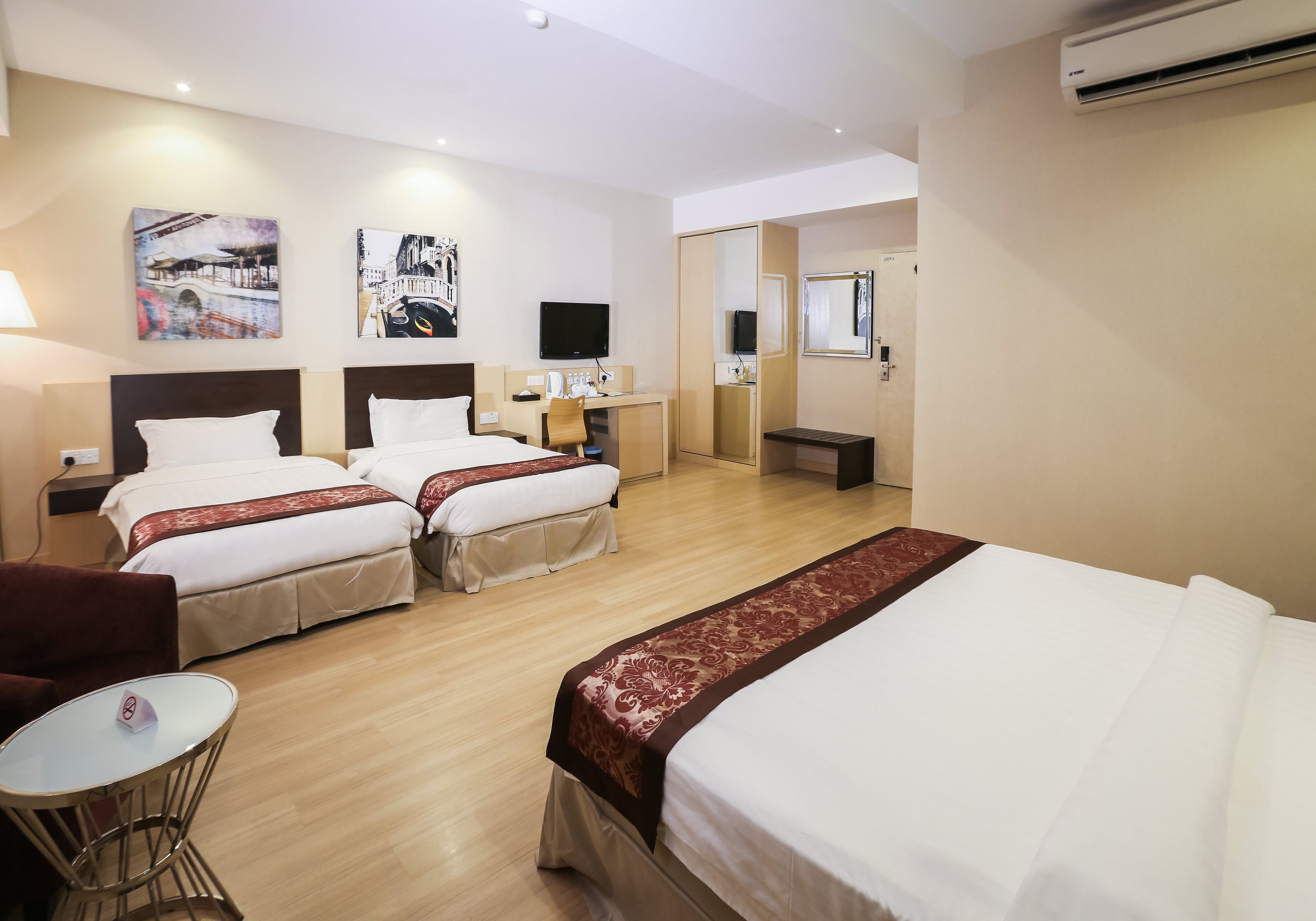 Een hotelkamer met twee bedden, een bureau, een stoel en kunstwerken aan de wanden.