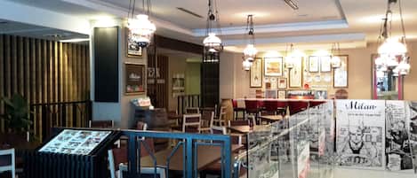 Interior de un restaurante con luces colgantes, cuadros en las paredes y una vitrina con el menú.