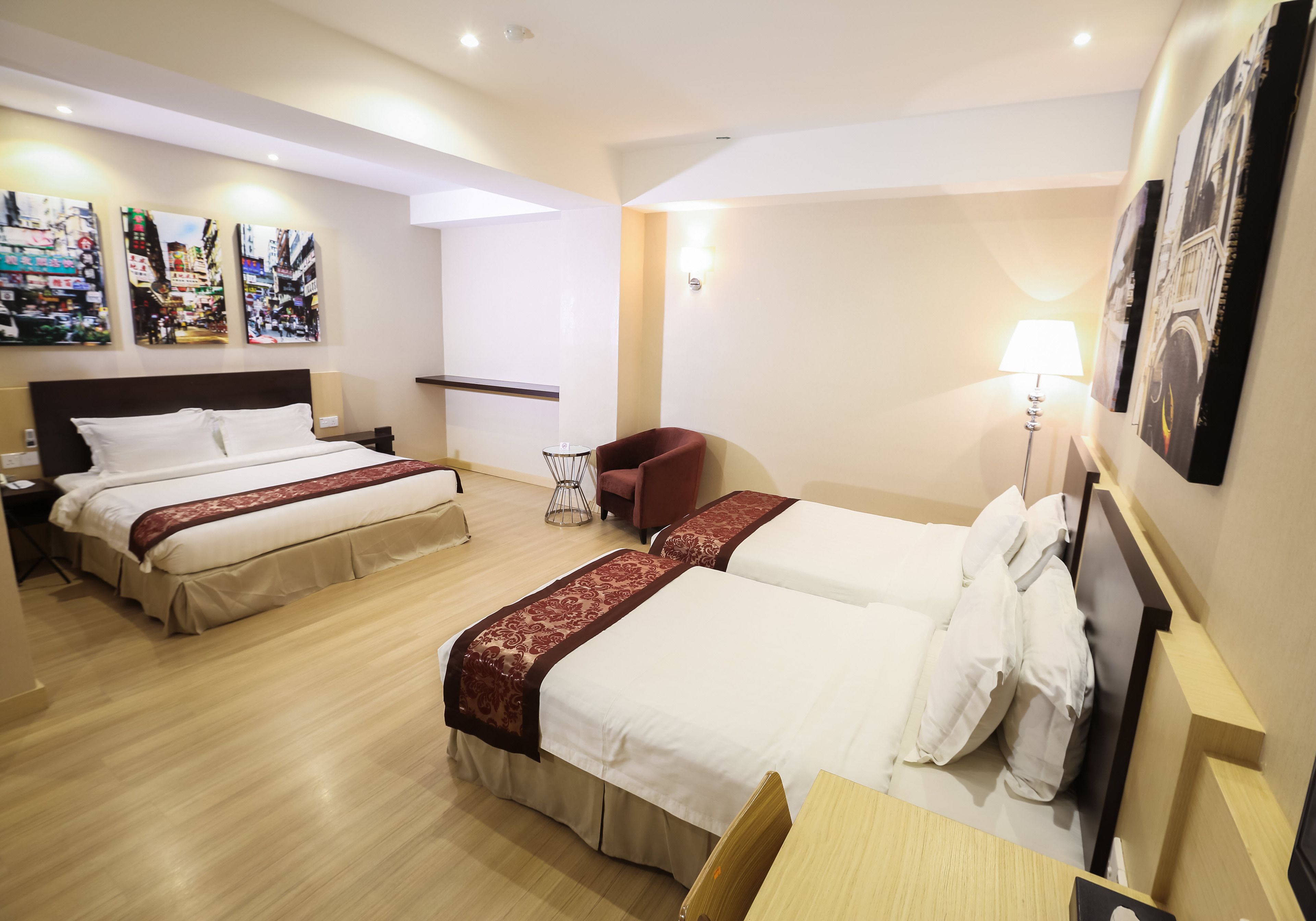 Una habitación de hotel con tres camas, un escritorio, una silla y decoración en la pared.