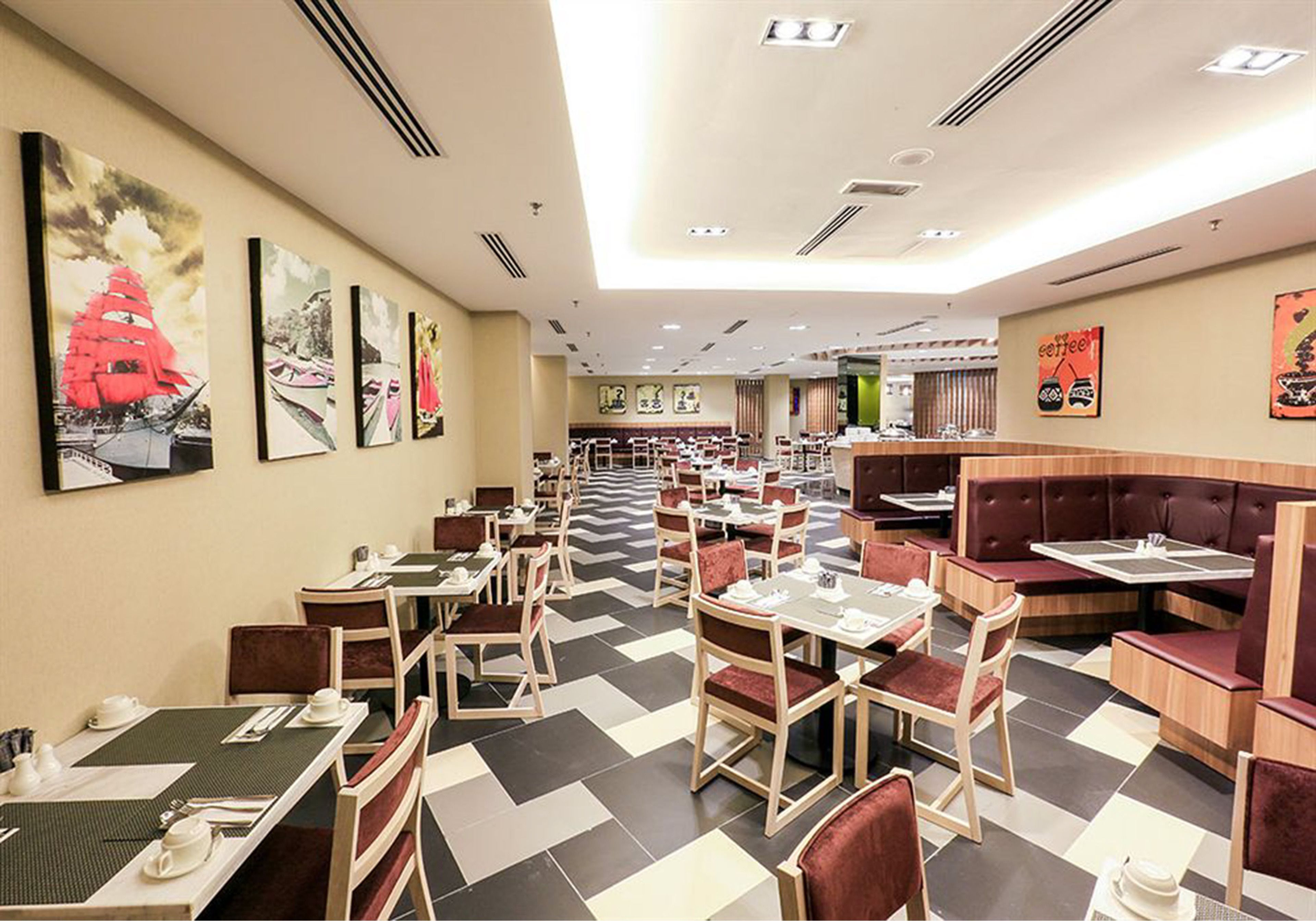 A restaurant with multiple dining tables and booths, a checkered floor, and artwork on the walls.