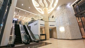 Un hall d’entrée spacieux doté d’escalators, d’un grand élément décoratif au plafond et d’une architecture moderne.