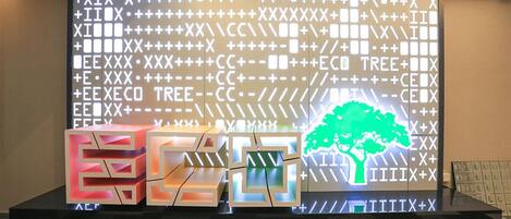Una moderna zona de recepción con una gran pared iluminada que muestra varios símbolos y un gráfico de un árbol.