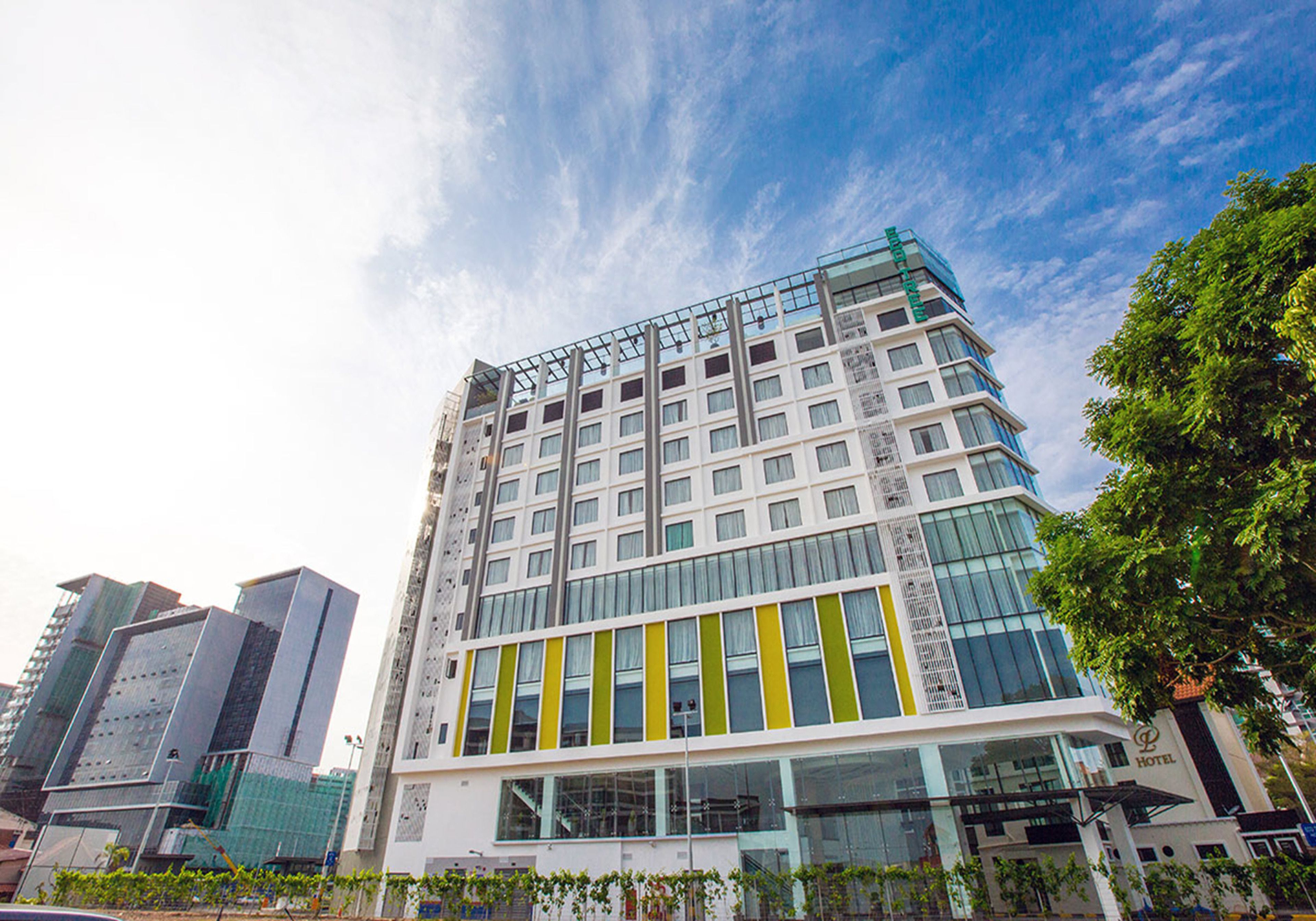 A modern hotel with multiple floors, large windows, and a prominent green stripe on the facade.