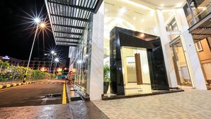 Une entrée d’hôtel moderne, dotée d’une allée couverte, de portes en verre et d’un intérieur bien éclairé.