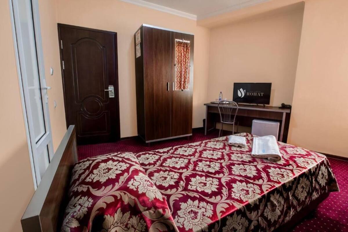 A hotel room with a bed, a wardrobe, a desk, and a television.