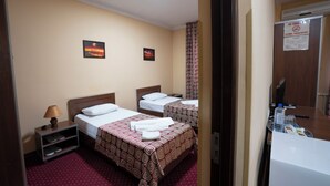 A hotel room with two beds, a nightstand, a lamp, and a bathroom with a towel rack. - Rohat Hotel (Tashkent)