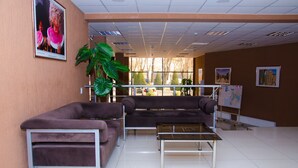 A waiting area with two sofas, a coffee table, and a large potted plant. - Rohat Hotel (Tashkent)