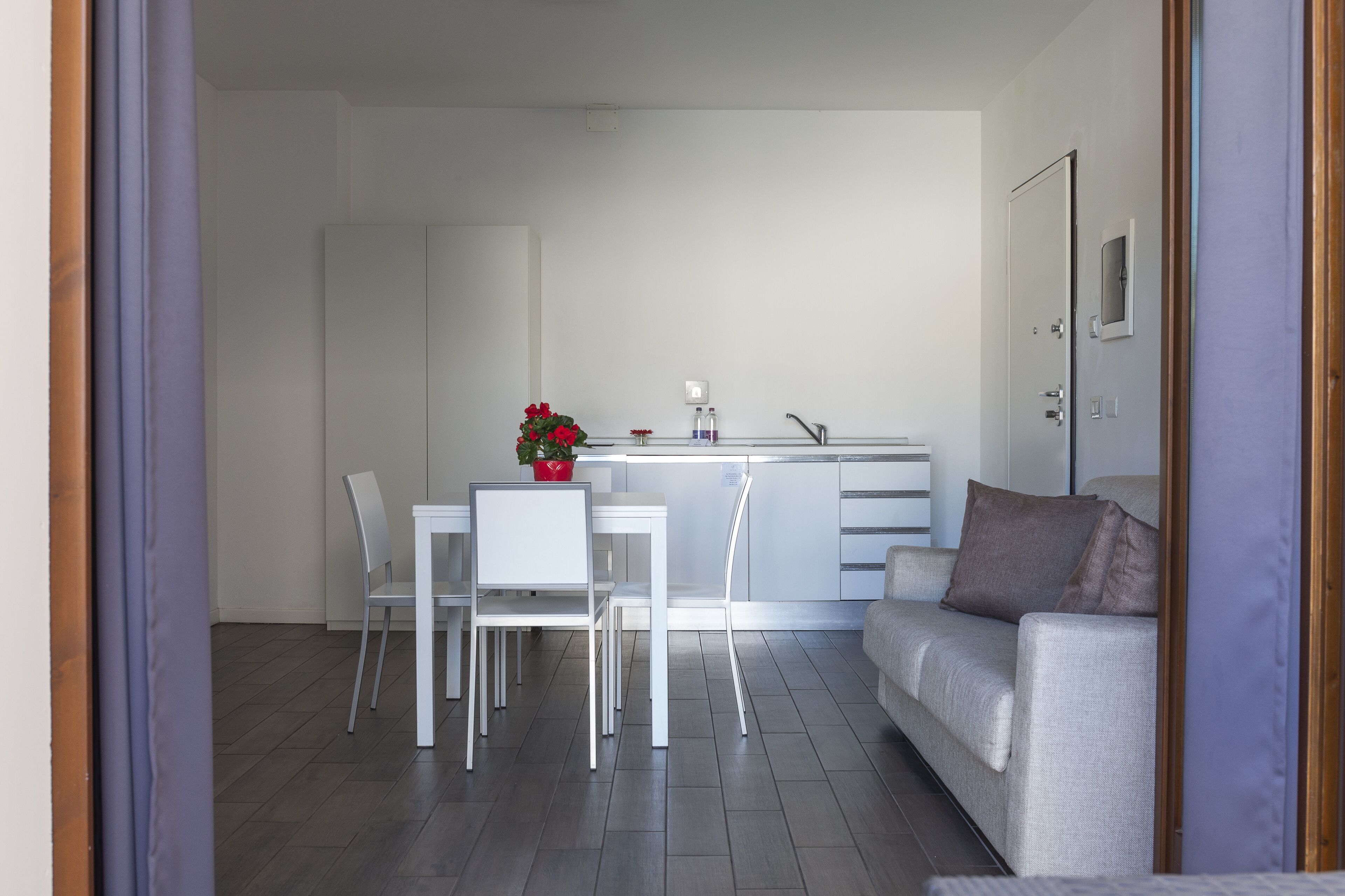 Un espai de vida modern i minimalista amb zona de menjador, sofà i cuina.