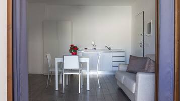 Un espai de vida modern i minimalista amb zona de menjador, sofà i cuina.