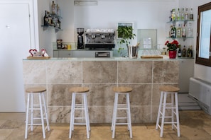 A kitchen with a marble island, espresso machine, and bar stools. - The Florence Hills Resort & Wellness (Pelago)