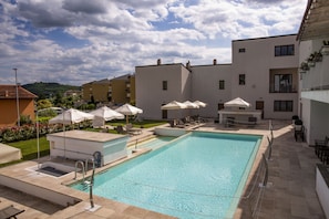 Relax by the rectangular pool surrounded by a modern building with balconies and comfortable lounge seating.