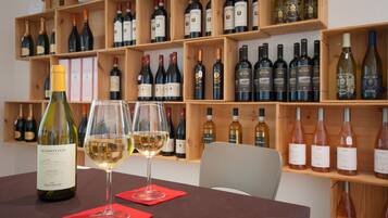 A wine tasting room with a wooden wine rack filled with various bottles. Two wine glasses are on a table in front of the rack.