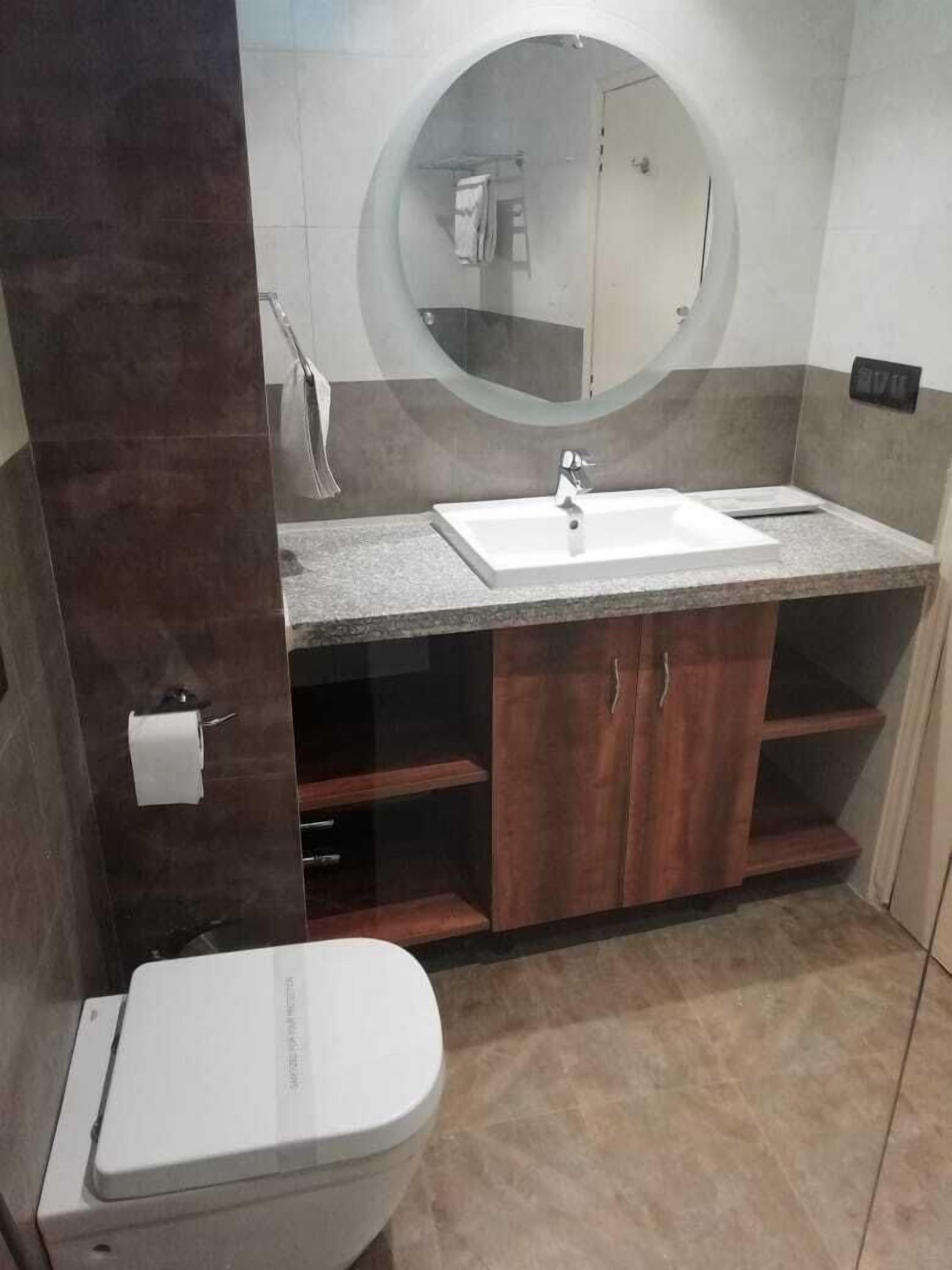 A bathroom with a toilet, sink, and mirror.